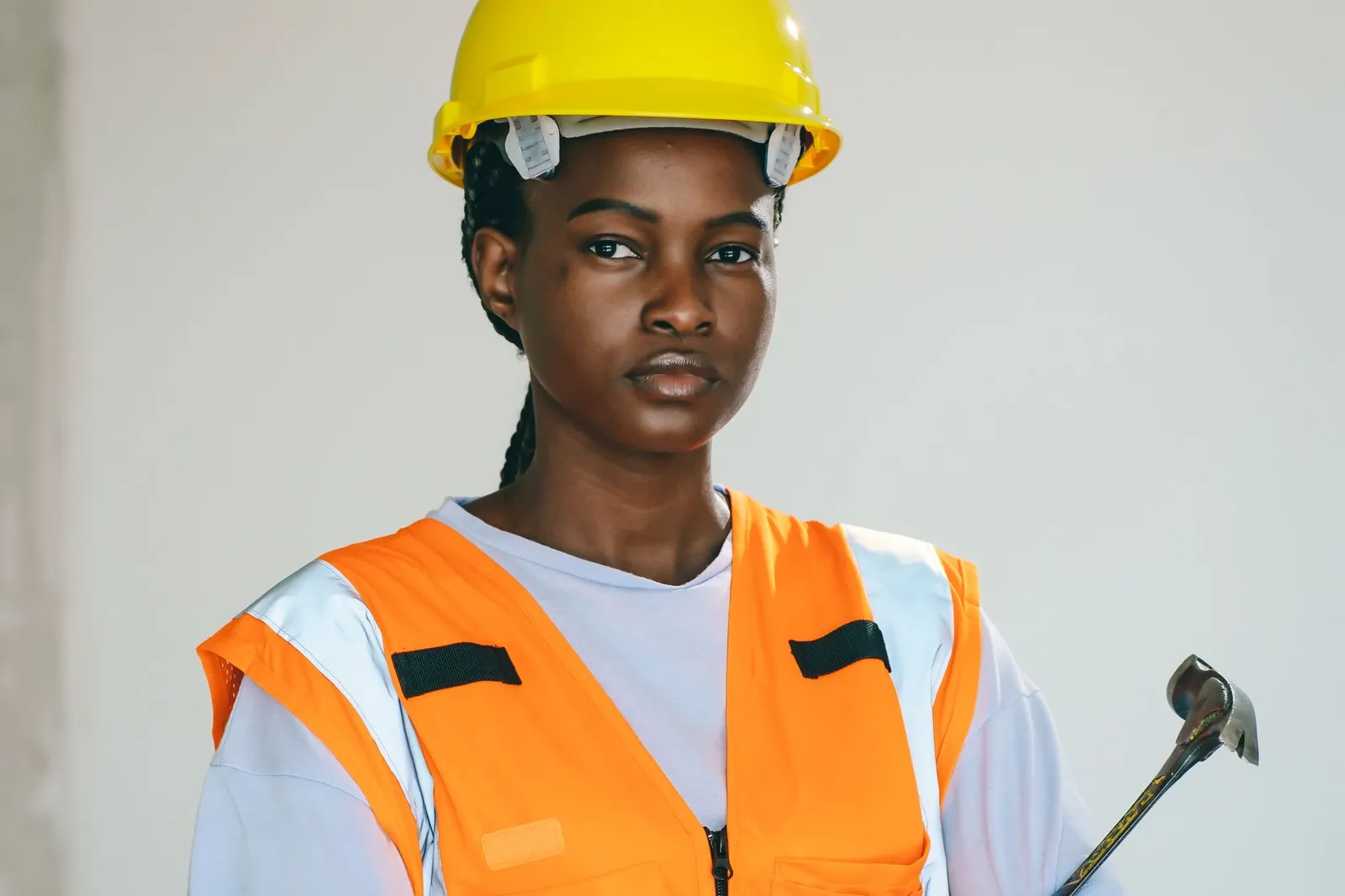 A woman in a hard hat holds a hammer on a job site